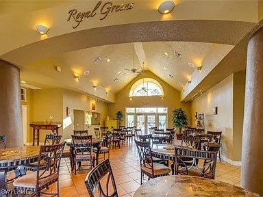 dining area featuring high vaulted ceiling, light tile patterned floors, beamed ceiling, ceiling fan, and decorative columns