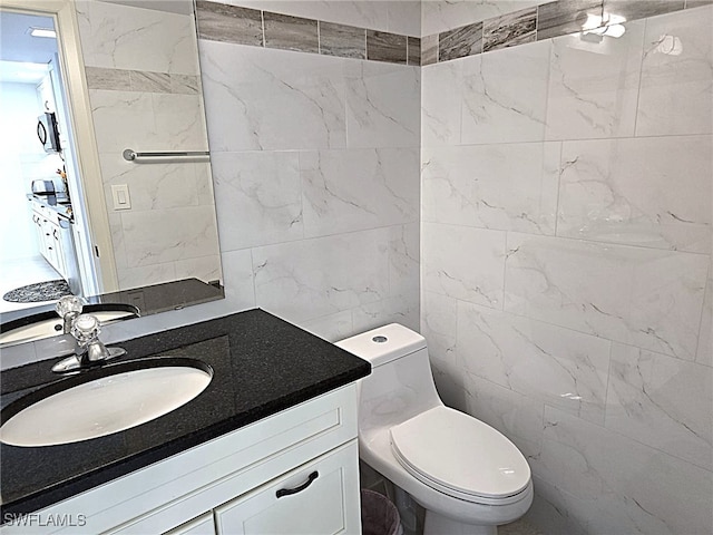 half bathroom with tile walls, toilet, and vanity