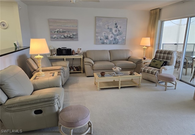 living area with a ceiling fan and carpet