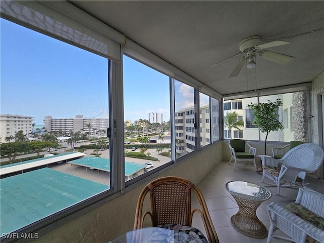 sunroom featuring a view of city and a ceiling fan