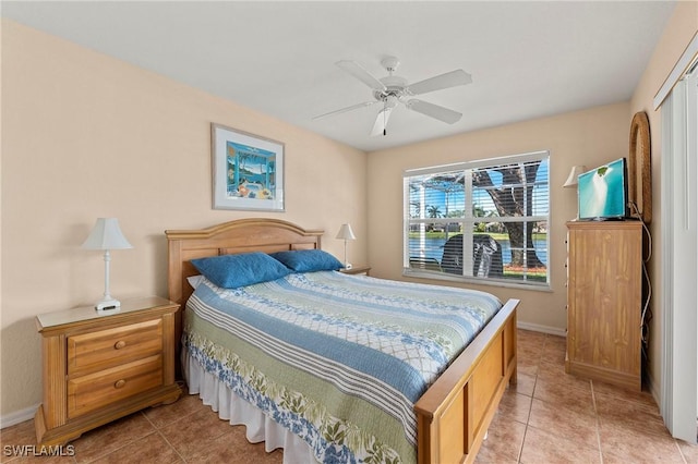 bedroom with light tile patterned floors, a closet, ceiling fan, and baseboards