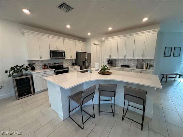 kitchen with a kitchen breakfast bar, backsplash, visible vents, stainless steel appliances, and a sink