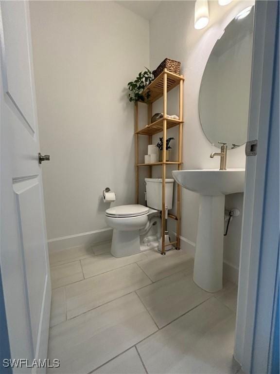 half bathroom featuring toilet, baseboards, and tile patterned flooring