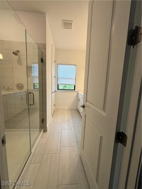 full bathroom with a stall shower, vanity, baseboards, and visible vents