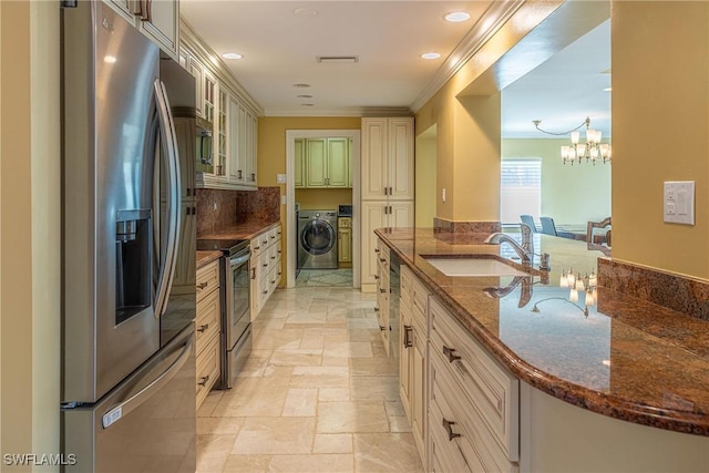 419 Pine Ave, Naples, FL 34108 - kitchen with ornamental molding, cream cabinetry, appliances with stainless steel finishes, a sink, and washer and dryer