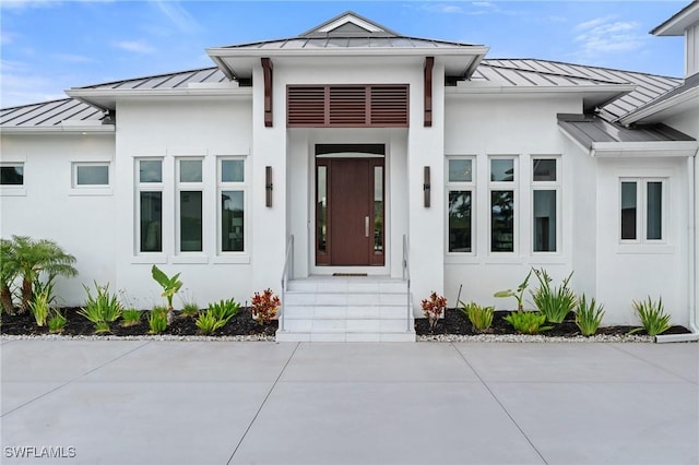 doorway to property with stucco siding, a standing seam roof, and metal roof