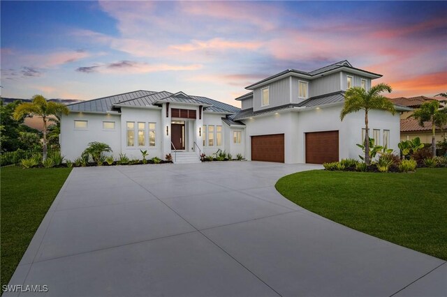 view of front facade featuring a standing seam roof, driveway, a front lawn, and a garage
