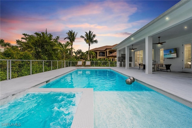 pool at dusk with a jacuzzi, a fenced in pool, a ceiling fan, fence, and a patio