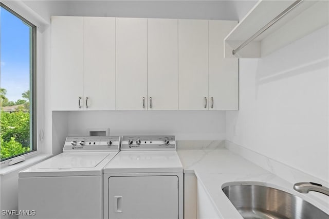 washroom featuring washing machine and clothes dryer, plenty of natural light, a sink, and cabinet space