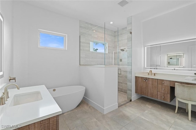 bathroom featuring a shower stall, a freestanding tub, a sink, and double vanity