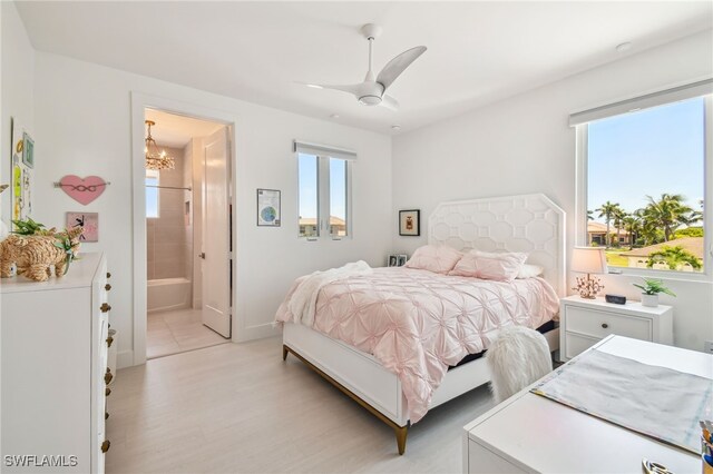 bedroom featuring ceiling fan with notable chandelier, ensuite bathroom, baseboards, and light wood-style floors