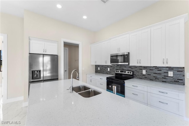 kitchen featuring tasteful backsplash, baseboards, white cabinets, appliances with stainless steel finishes, and a sink