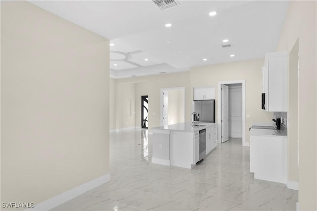 kitchen featuring visible vents, baseboards, a sink, appliances with stainless steel finishes, and an island with sink