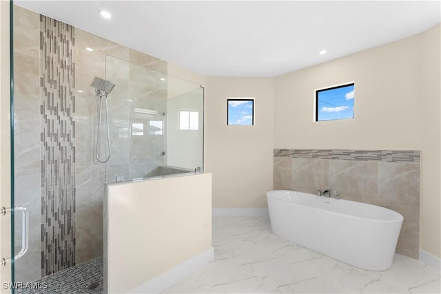 full bath featuring a tile shower, a freestanding tub, marble finish floor, and recessed lighting