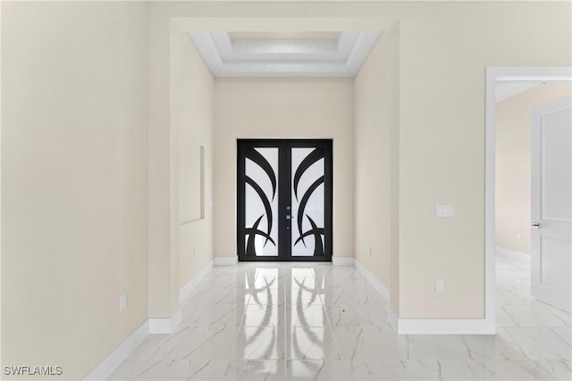entryway featuring marble finish floor, baseboards, and a raised ceiling