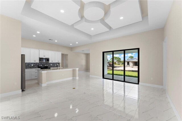 unfurnished living room featuring recessed lighting, a sink, marble finish floor, and baseboards