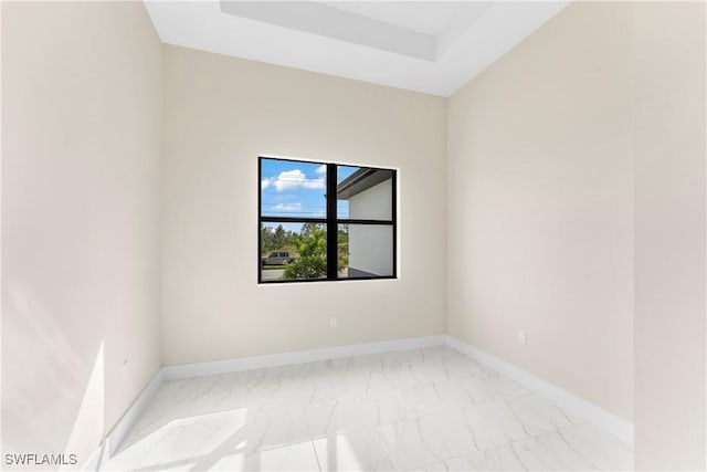 spare room featuring marble finish floor and baseboards