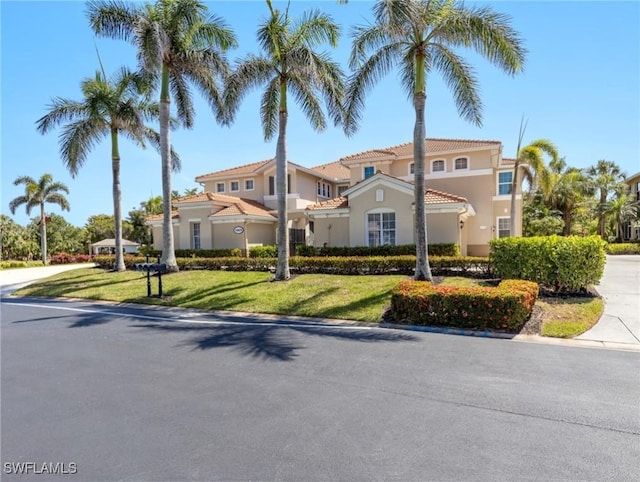 mediterranean / spanish-style home with a tiled roof, stucco siding, and a front yard
