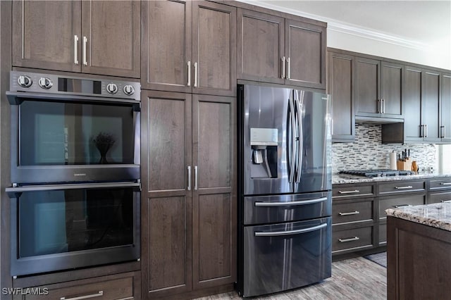 14696 Indigo Lakes Cir, Naples, FL 34119 - kitchen featuring light stone counters, dark brown cabinetry, appliances with stainless steel finishes, and tasteful backsplash