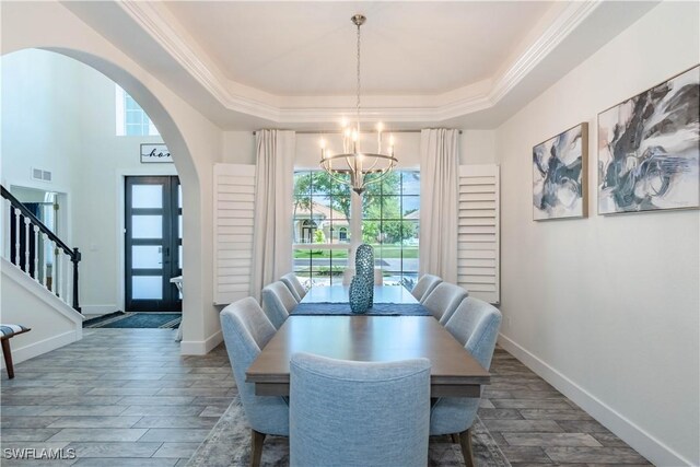 14696 Indigo Lakes Cir, Naples, FL 34119 - dining space featuring wood finished floors, arched walkways, an inviting chandelier, a tray ceiling, and visible vents