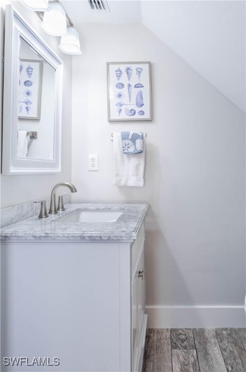 14696 Indigo Lakes Cir, Naples, FL 34119 - bathroom with baseboards, vaulted ceiling, vanity, and wood finished floors