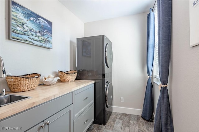 14696 Indigo Lakes Cir, Naples, FL 34119 - washroom with light wood-type flooring, baseboards, stacked washer / dryer, and cabinet space