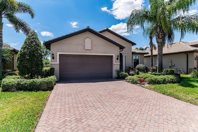 single story home with a tiled roof, a garage, stucco siding, and decorative driveway