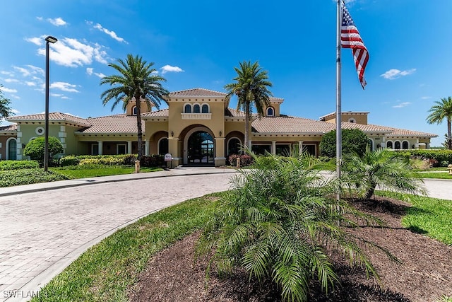 view of front facade featuring curved driveway, stucco siding, and a tile roof