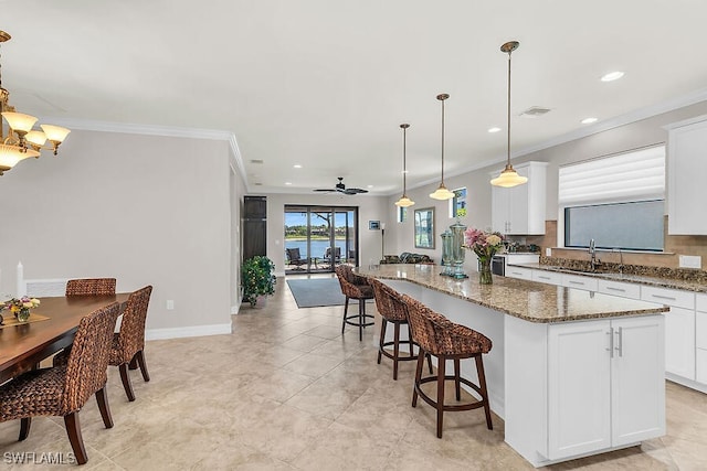 kitchen with a center island, dark stone counters, crown molding, and recessed lighting