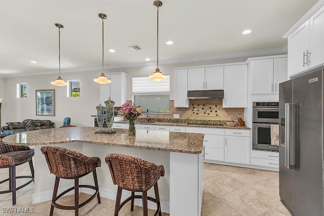 kitchen featuring visible vents, a breakfast bar, under cabinet range hood, white cabinetry, and stainless steel appliances