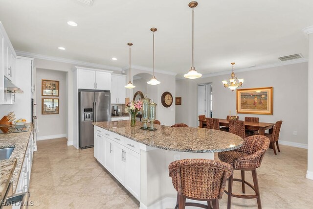 kitchen featuring visible vents, a kitchen island, a breakfast bar, under cabinet range hood, and high end refrigerator