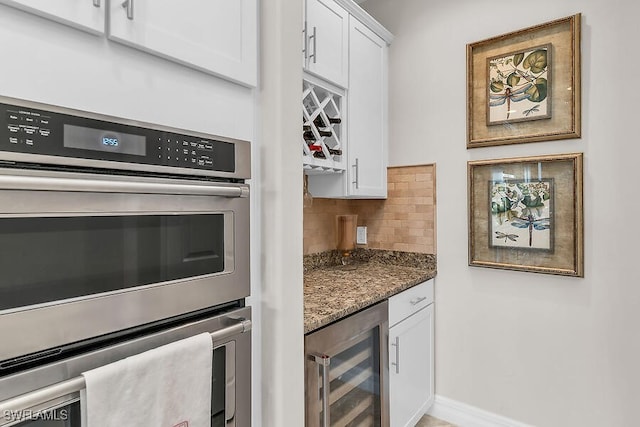 bar featuring baseboards, backsplash, stainless steel double oven, a dry bar, and wine cooler