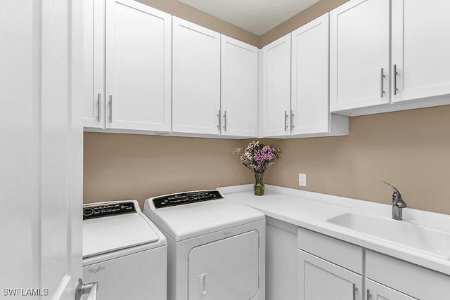 washroom featuring a sink, washing machine and clothes dryer, and cabinet space