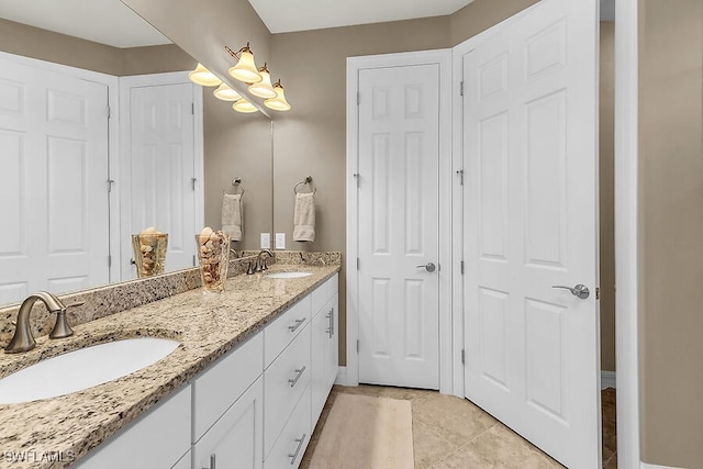 bathroom with a chandelier, double vanity, a sink, and tile patterned flooring