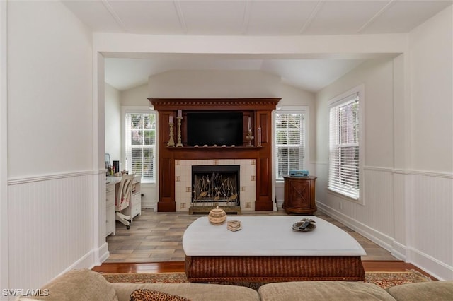 living room featuring vaulted ceiling, wood finished floors, a tile fireplace, and a healthy amount of sunlight