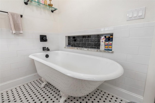bathroom with tile patterned flooring, wainscoting, a freestanding tub, and tile walls
