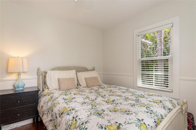 bedroom with wood finished floors and wainscoting