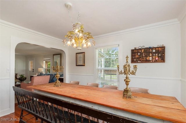 dining area featuring arched walkways, a wealth of natural light, ornamental molding, and an inviting chandelier