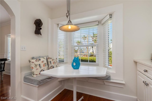 dining room with arched walkways, wood finished floors, breakfast area, and baseboards