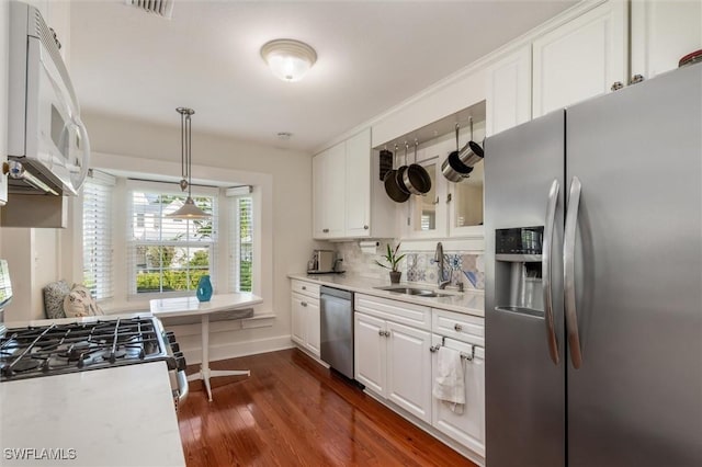 kitchen featuring white cabinets, dark wood-style floors, stainless steel appliances, light countertops, and a sink