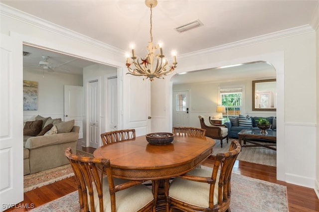 dining room featuring wood finished floors, ceiling fan with notable chandelier, arched walkways, ornamental molding, and visible vents