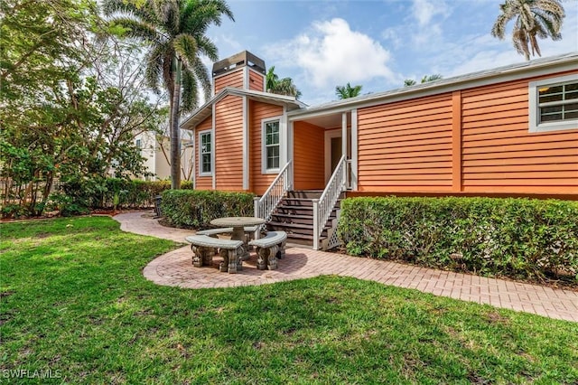 view of front of house featuring a chimney and a front lawn