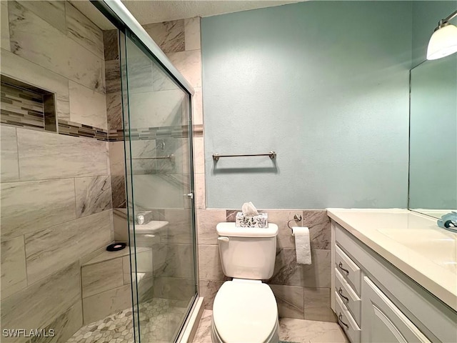 bathroom with toilet, vanity, tile walls, and a stall shower