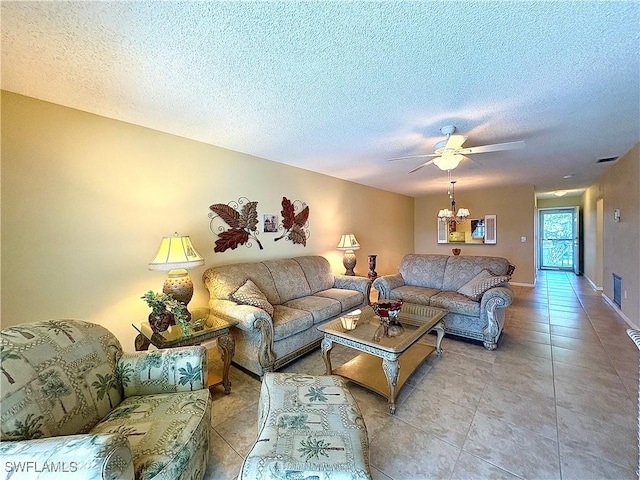 living area featuring a textured ceiling, ceiling fan with notable chandelier, light tile patterned floors, and visible vents