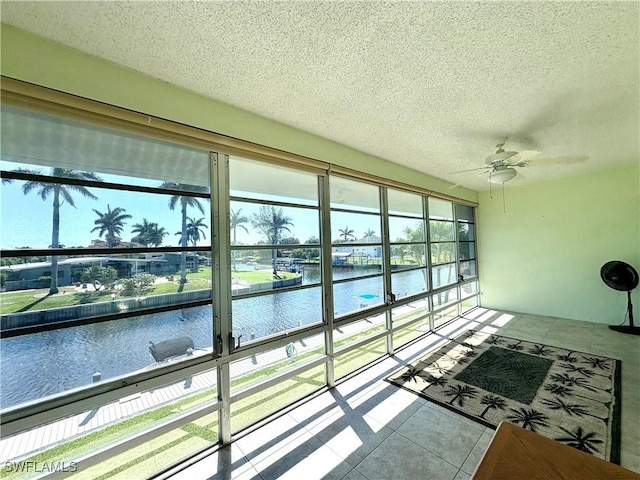 unfurnished sunroom with tile patterned floors, a textured ceiling, and a water view