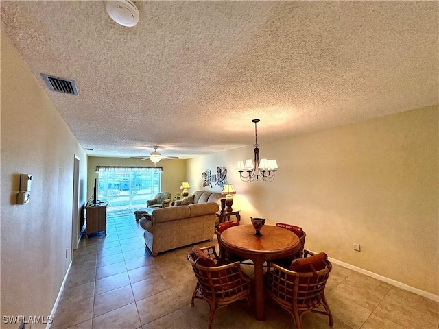 dining area featuring baseboards, tile patterned flooring, a textured ceiling, visible vents, and ceiling fan with notable chandelier