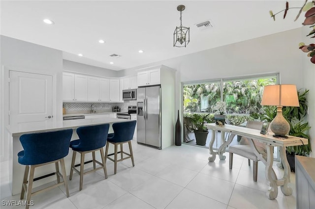 kitchen with tasteful backsplash, light countertops, white cabinets, visible vents, and appliances with stainless steel finishes