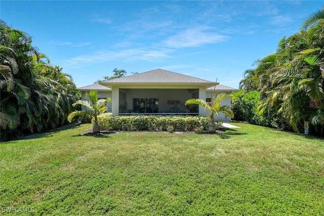 back of house featuring stucco siding, a sunroom, and a lawn