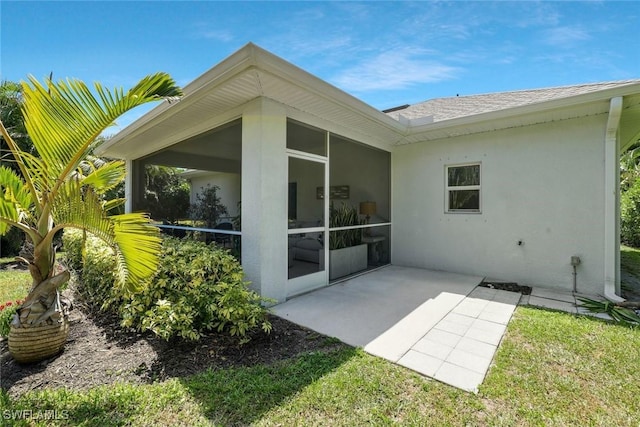 back of property featuring a sunroom, a shingled roof, stucco siding, and a patio area