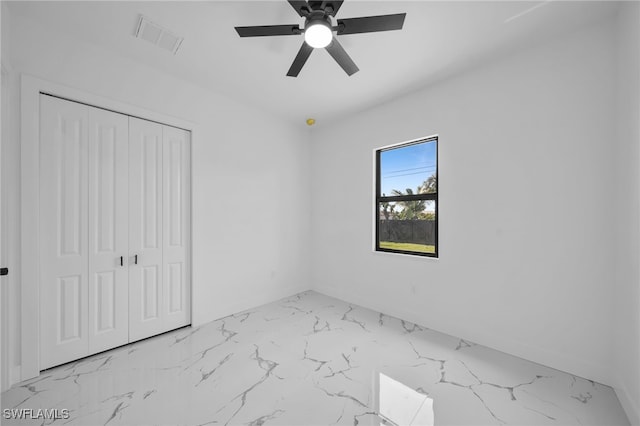 unfurnished bedroom featuring a closet, marble finish floor, ceiling fan, and visible vents